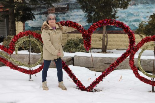 Lynda Brasz standing with Valentine's Heart Decoration in the parkette.